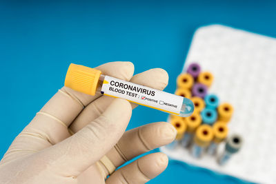 Close-up of hand holding paper against blue background