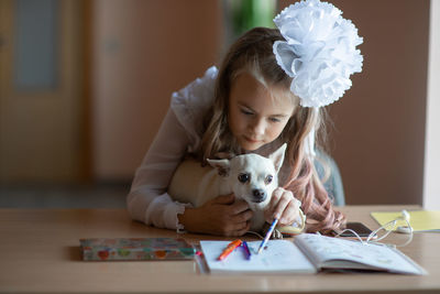 Girl with dog studying while sitting at home