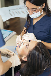Cropped image of dentists examining woman teeth at hospital