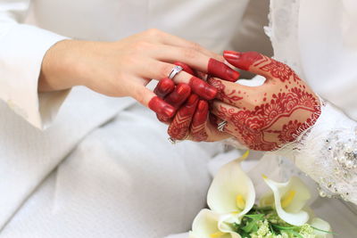 Midsection of bride putting ring in groom finger sitting on sofa during wedding