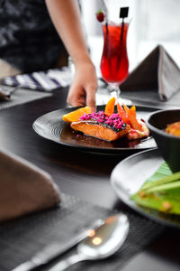 Midsection of woman holding plate with food on restaurant table