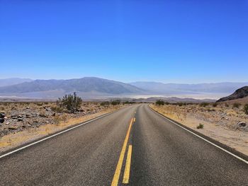 Road leading towards mountains against sky. take in the famous death valley