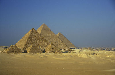 Old stone pyramids on desert landscape against clear sky