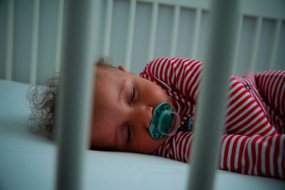 Toddler with pacifier sleeping on bed