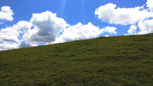Low angle view of green landscape against sky