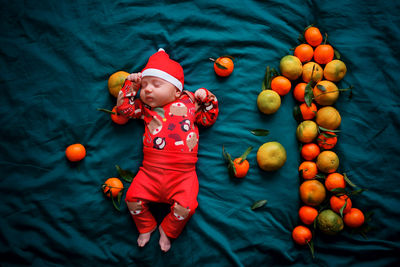 Christmas newborn sleeping baby in a red santa costume lies on a green background