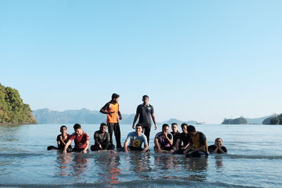 People on sea against clear sky