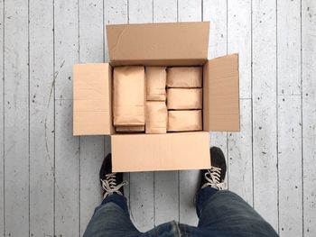 Low section of man with packages on wooden floor