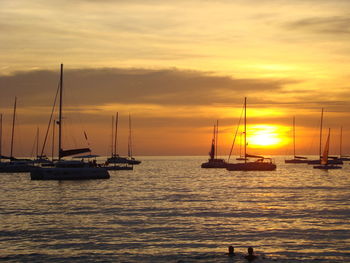 Sailboats in sea against sky during sunset
