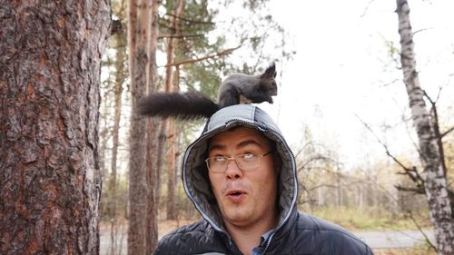 Portrait of mature man on tree trunk in forest
