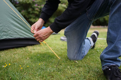 Low section of man holding umbrella on field