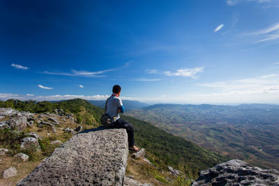 Rear view of man standing on rock against sky