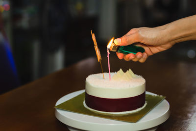 Woman lighting candle on a birthday cake at home.