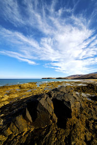 Scenic view of rocks by sea against sky