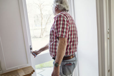 Senior man opening glass door on sunny day