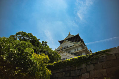 Low angle view of trees and building against sky