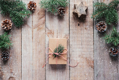 Christmas gift box wrapped in kraft paper with christmas tree branch on wooden background