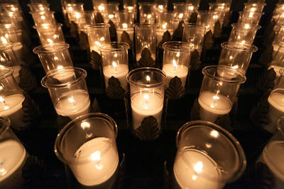 Full frame shot of lit tea light candles arranged in church