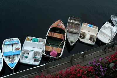 High angle view of boats moored in water, wooden board dock with flowers.