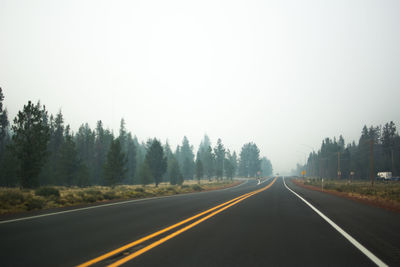 Road amidst trees against clear sky