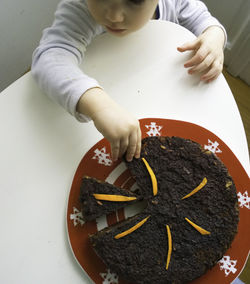 High angle view of cute boy picking cake from plate at home