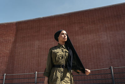 Young woman standing against wall