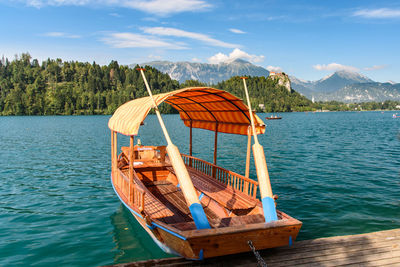 Boat moored on lake against sky