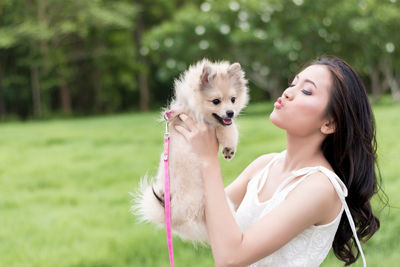 Close-up of woman carrying dog in park