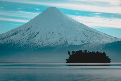 Scenic view of sea by snowcapped mountain against sky