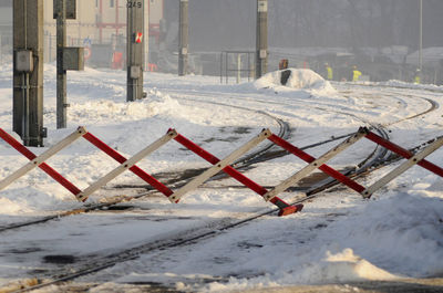 Snow covered railroad track by fence during winter