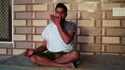 Young man sitting on wall at home