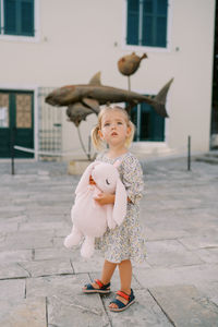 Portrait of young woman standing against wall