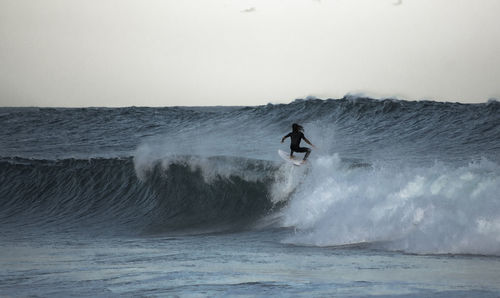 Person surfing in sea against sky