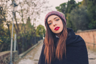 Portrait of woman standing on footpath