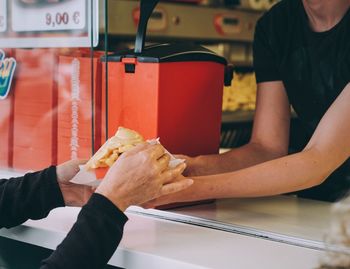 Cropped image of customer hands buying french fries from man