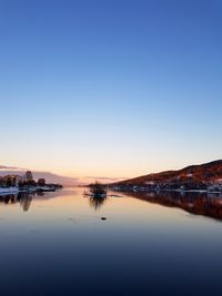 Scenic view of lake against clear sky at sunset