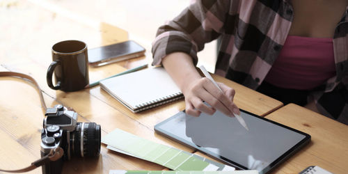 Midsection of man using mobile phone while sitting on table