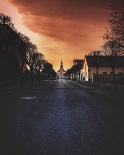 Road by trees against sky during sunset