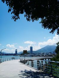 Bridge over river by city against blue sky