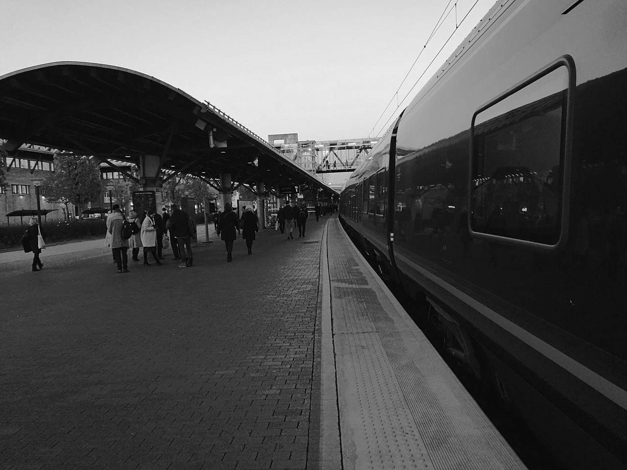 PEOPLE WAITING AT RAILROAD STATION AGAINST CLEAR SKY