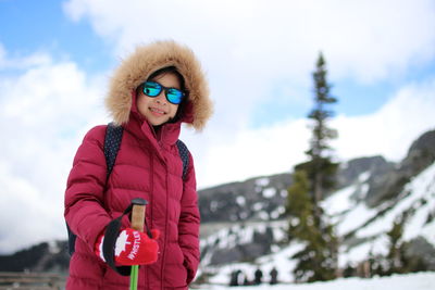 Portrait of woman standing by snow against sky