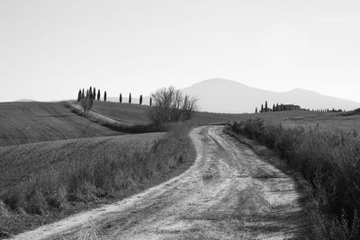 Dirt road on field against clear sky