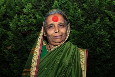 Portrait of smiling senior woman standing against trees
