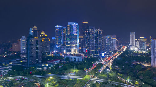 Illuminated buildings in city against clear sky at night