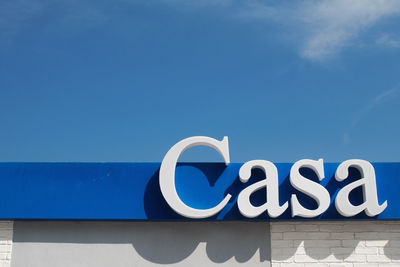 Low angle view of information sign against blue sky