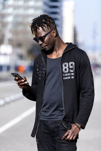 Young man using mobile phone standing in city