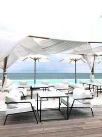 Chairs and table on beach against sky