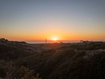 Scenic view of silhouette field against orange sky