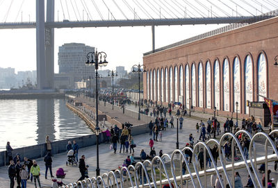 People on bridge in city against sky