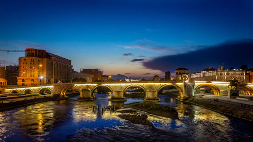 Illuminated bridge over river against sky at night